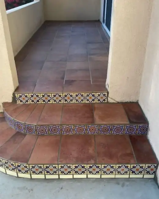 A small entry stoop with terracotta tile treads and patterned tile risers
