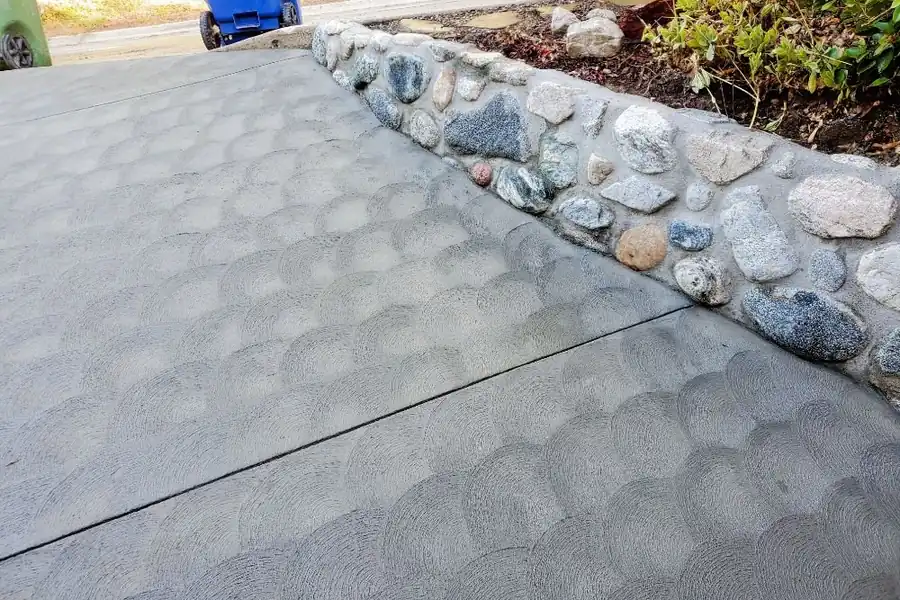A new concrete driveway beside a river rock wall on a Mt Washington lot